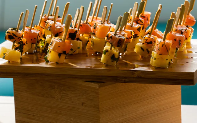 Bouchées de cocktail dînatoire sur un plateau en bois, la mer en arrière-plan