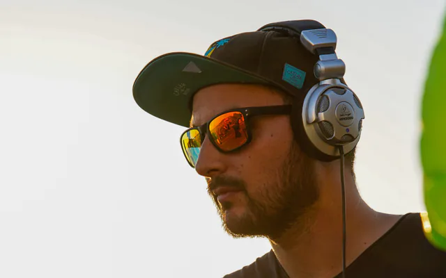 DJ à casquette et lunettes derrière ses platines, badge ADJM Event