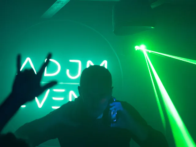 DJ aux platines avec un laser vert et un logo ADJM en soirée