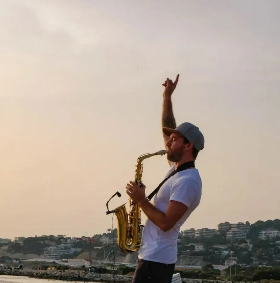 Saxophoniste qui joue au coucher du soleil face à la mer à Marseille