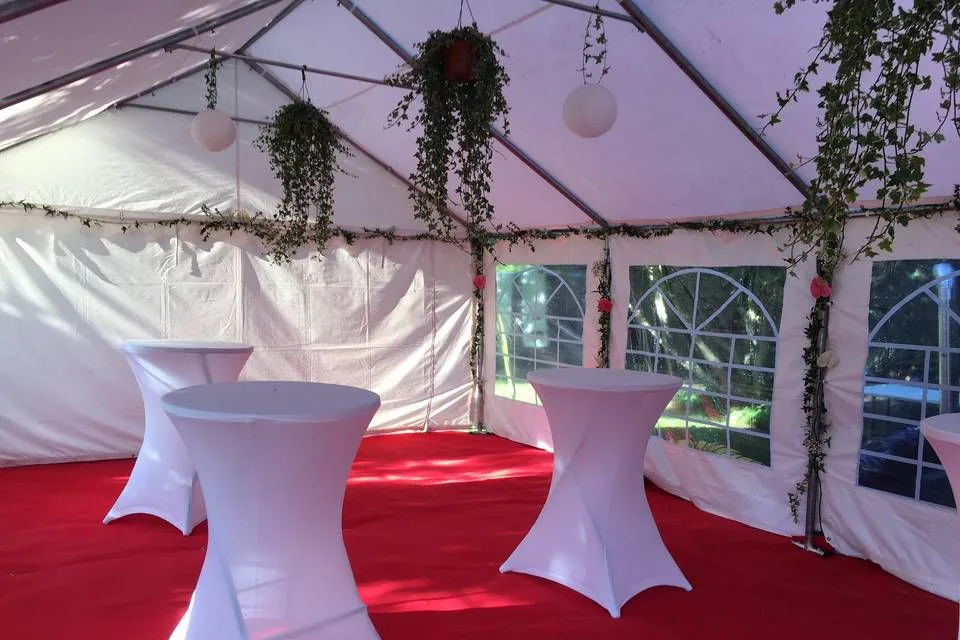 Tente de réception blanche avec des mange-debout sur une moquette rouge